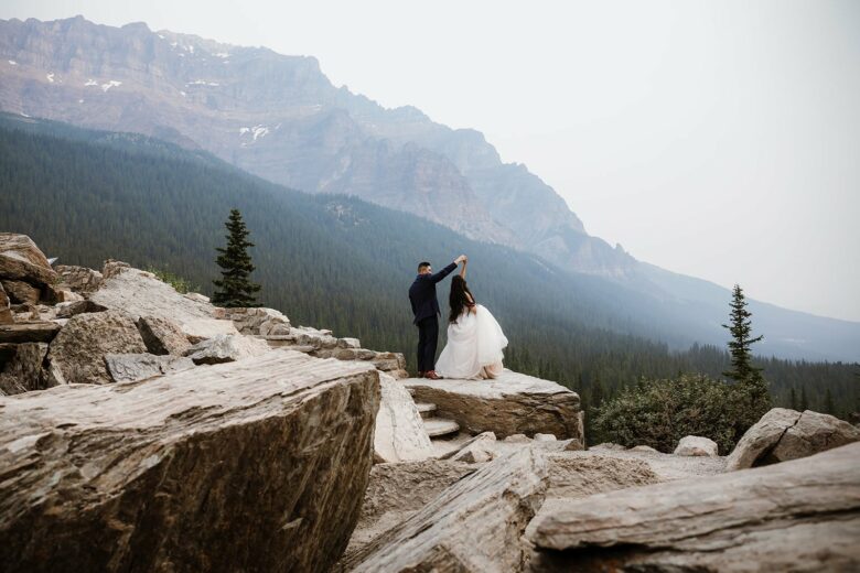 Bride and groom dancing on a rock surrounded by mountains in Banff.