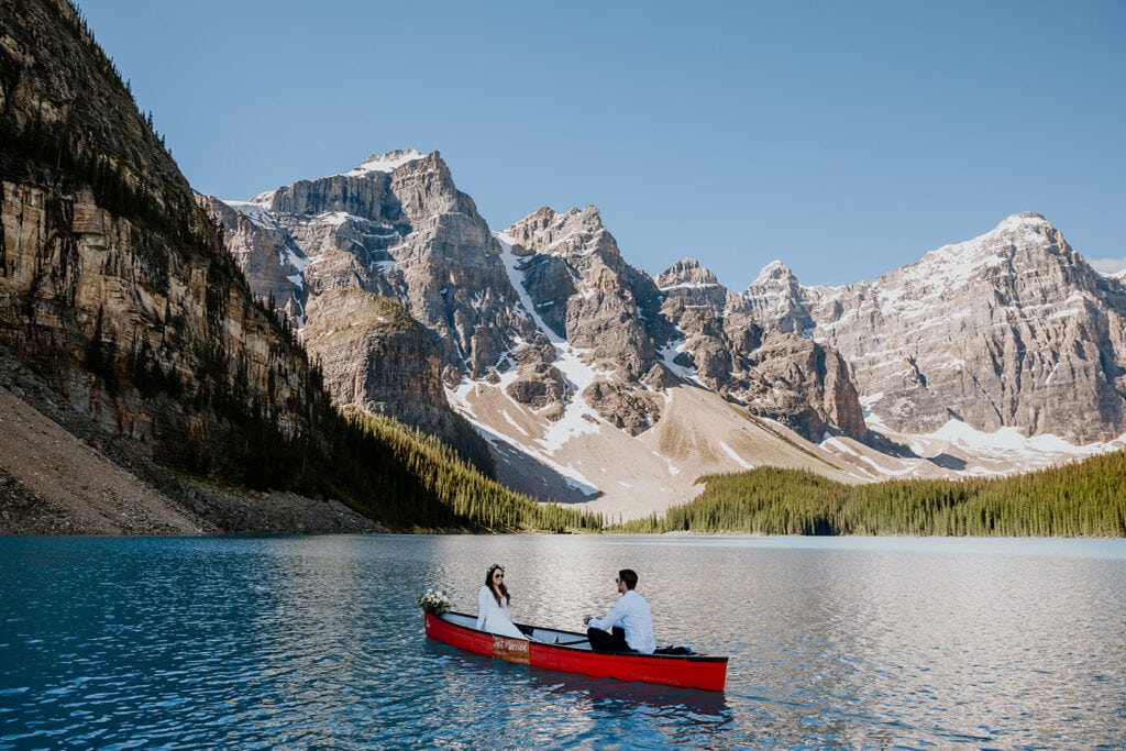 Newly wed having a canoe ride at Moraine Lake on a red canoe in Banff.