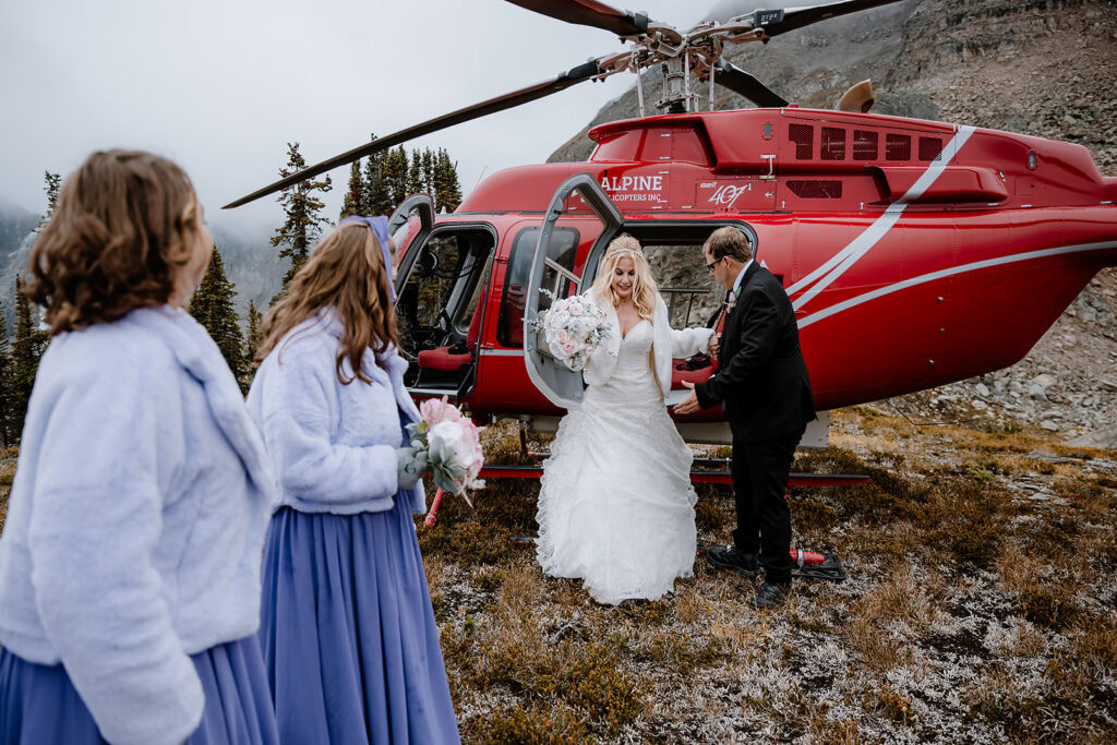 Couple getting out of the helicopter with their daughters on the mountain side in Banff on their wedding day