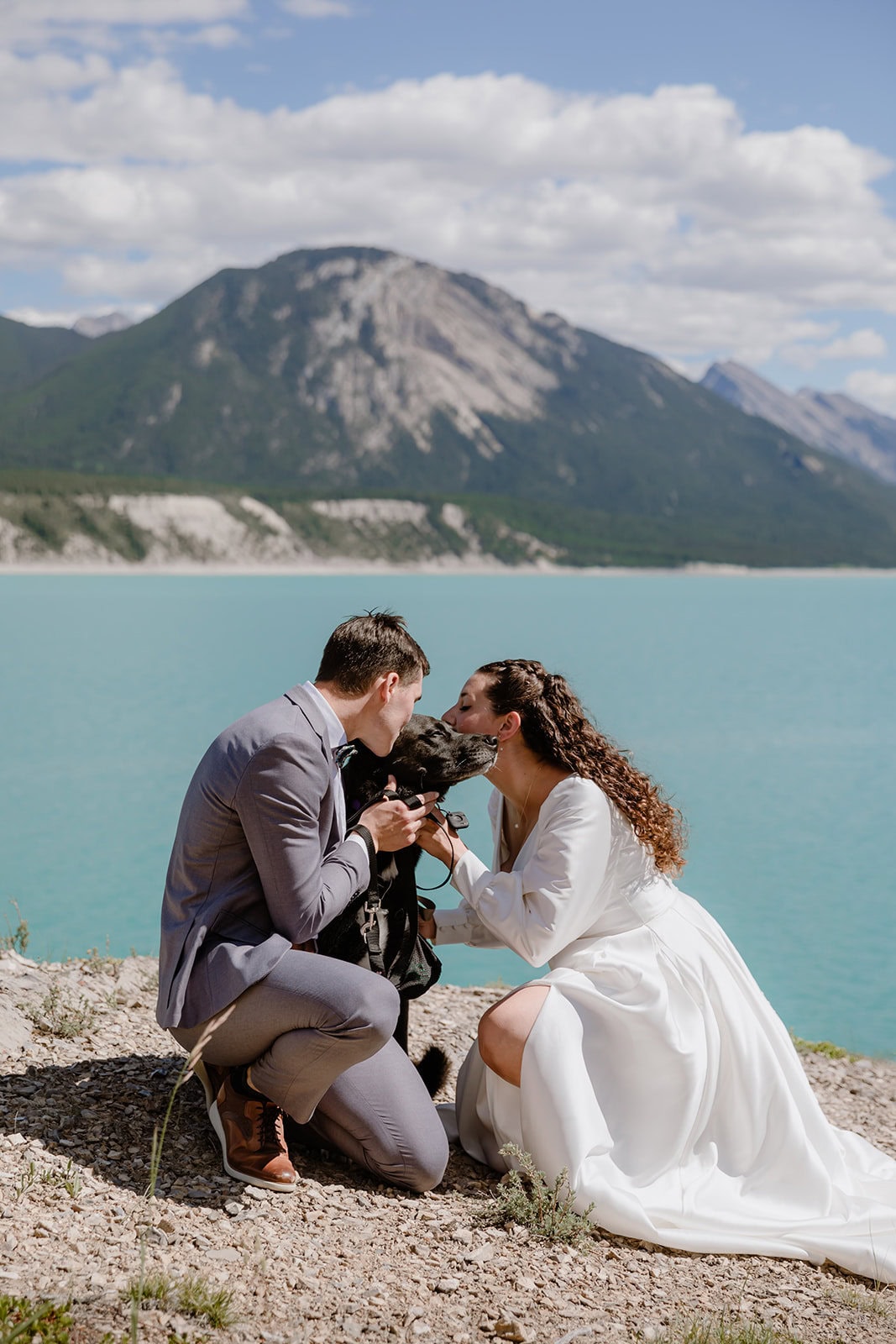 Couple with their dog overlooking a blue lake of their wedding day 
