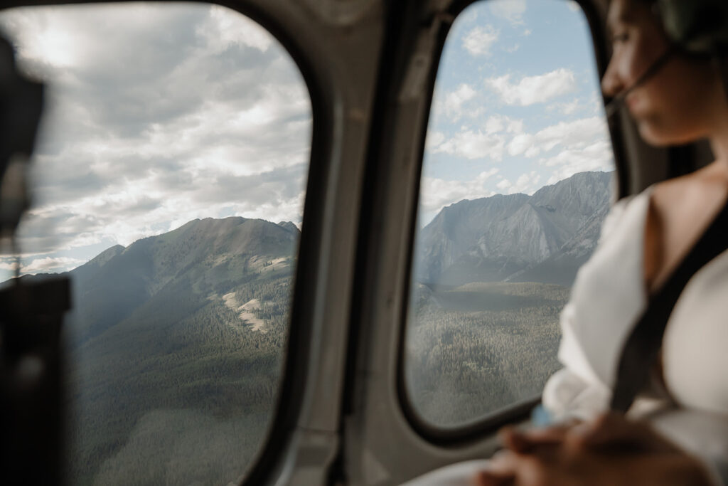Bride over looking out the helicopter window on their elopement day in banff