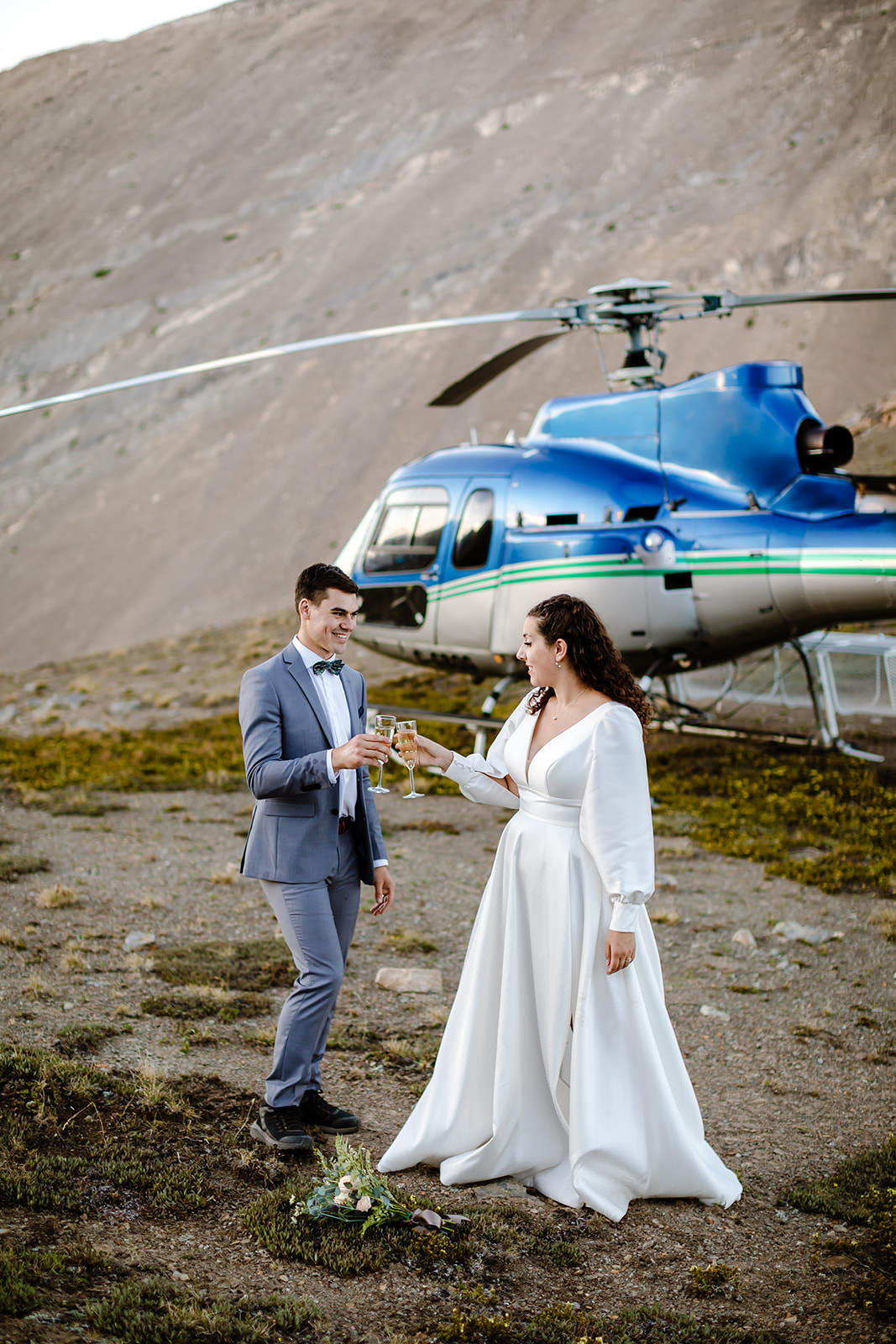 Bride and groom making a toast on their wedding day in Banff in front of a blue helicopter