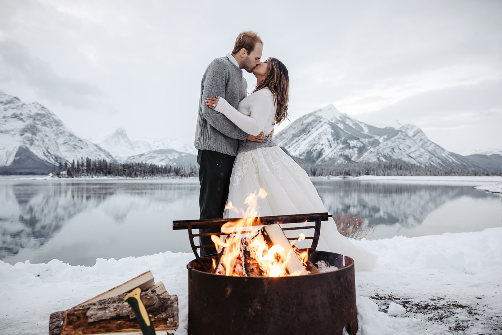 Bride and groom on their winter wedding in Banff slow dancing in front of the camp fire