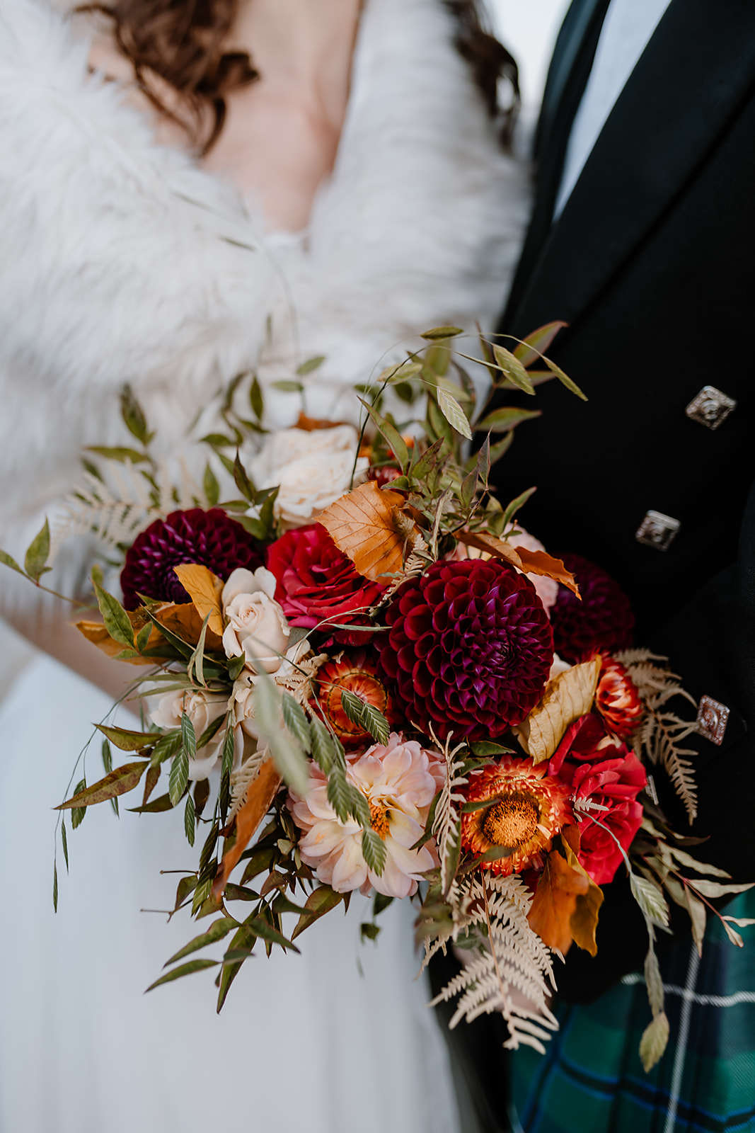 a couple stands with a beautiful autumn inspired bouquet during their mountain elopement 