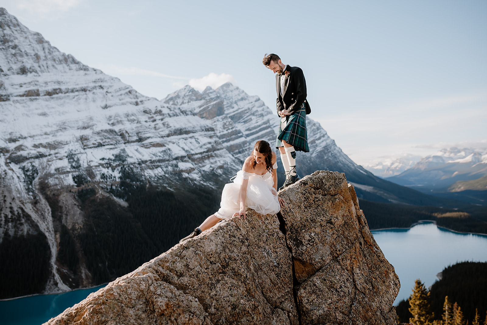 a bride skootches down a rock during her Bow Lake Wedding
