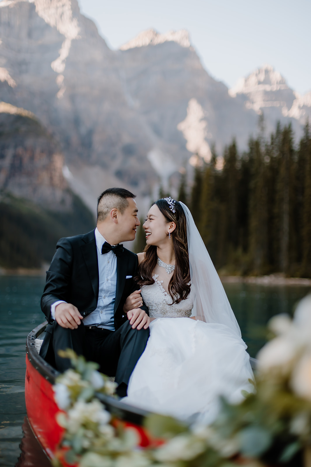 a bride and groom sharing a sweet moment while sitting in a red canoe