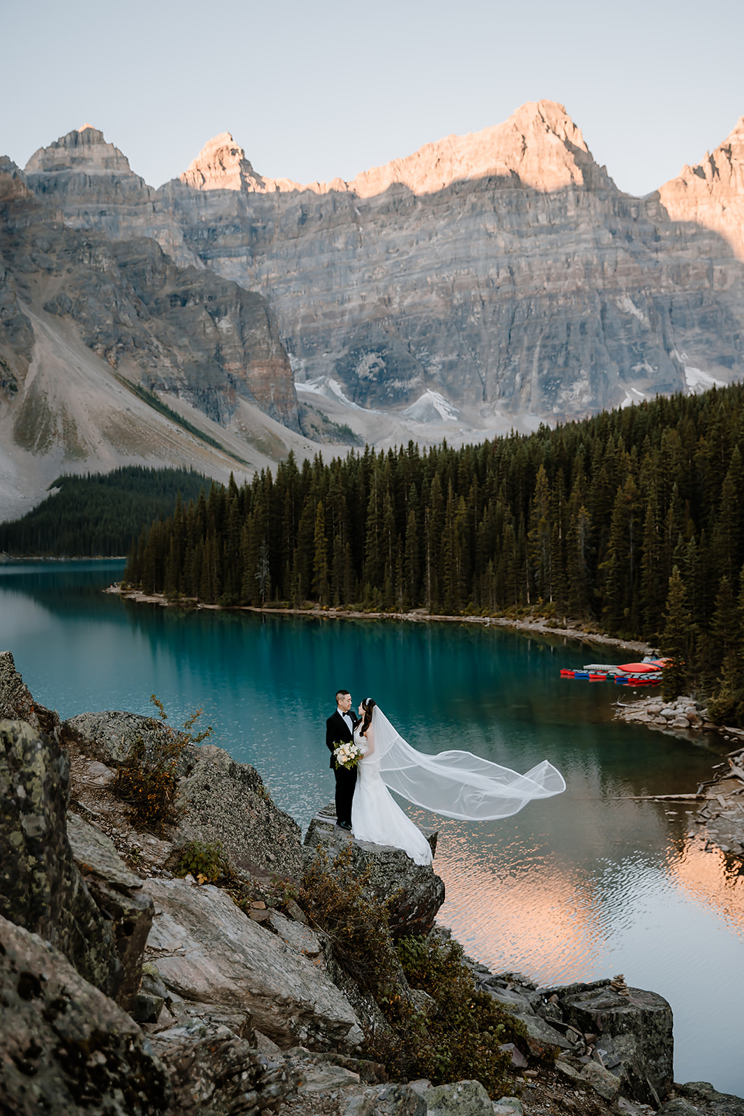 brides and groom looking at each other and the brides veil is blowing the in the wind - pre-wedding canoe ride photoshoot at Moraine Lake 