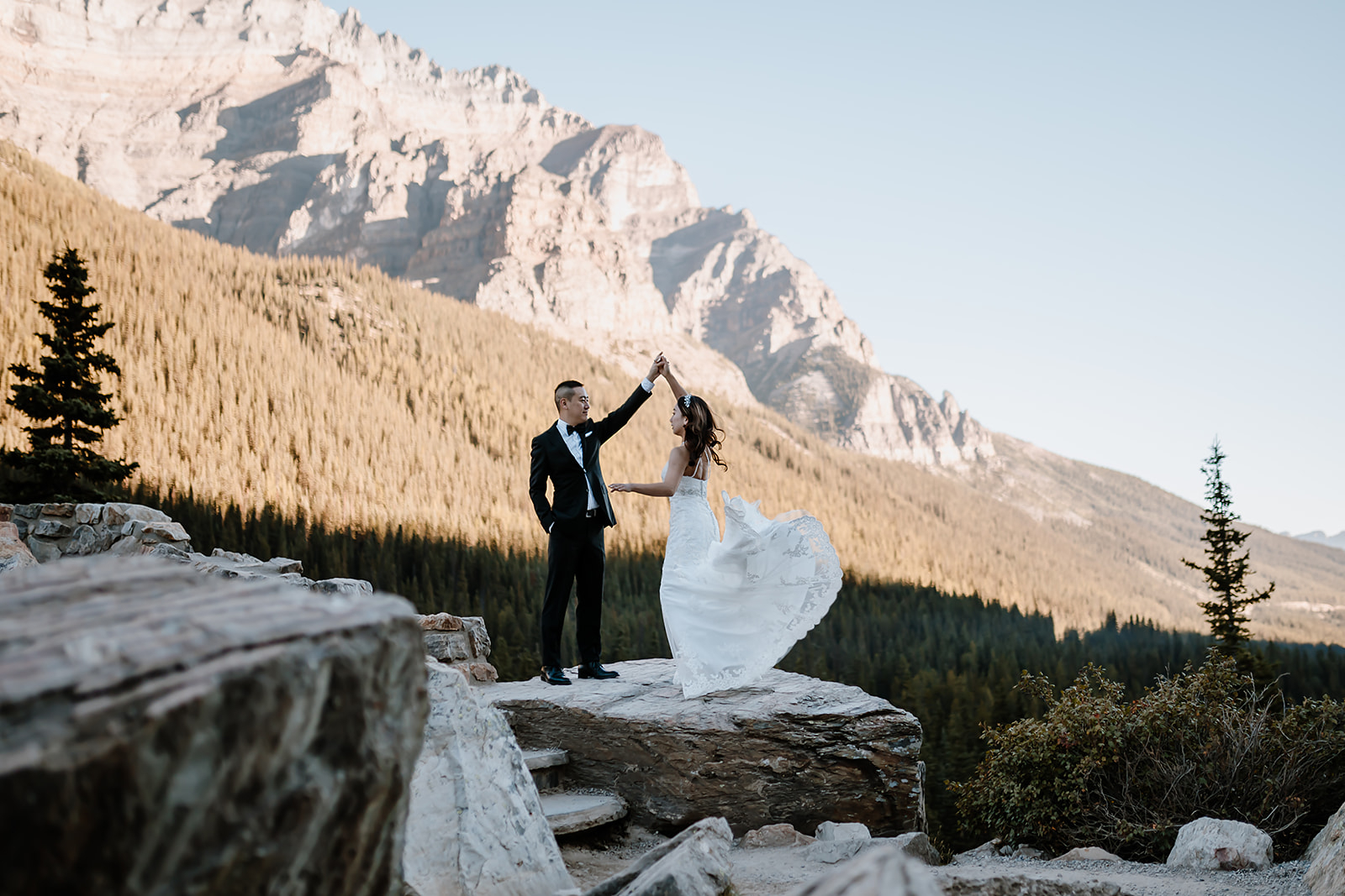 bride and groom dancing on the rocks as the sun comes up 