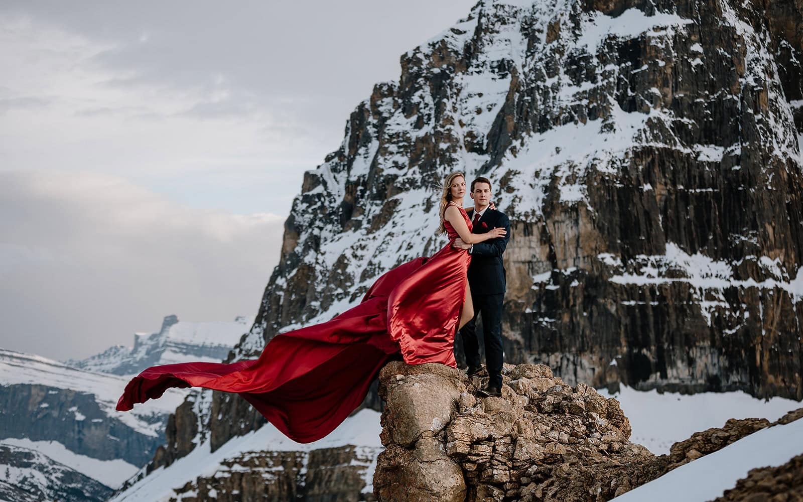 Bride’s dress flowing in the wind on a snowy cliff edge