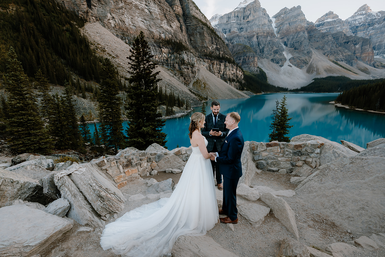get-married-in-Banff a bride and groom with wedding officiant getting married on a mountain beside a blue lake