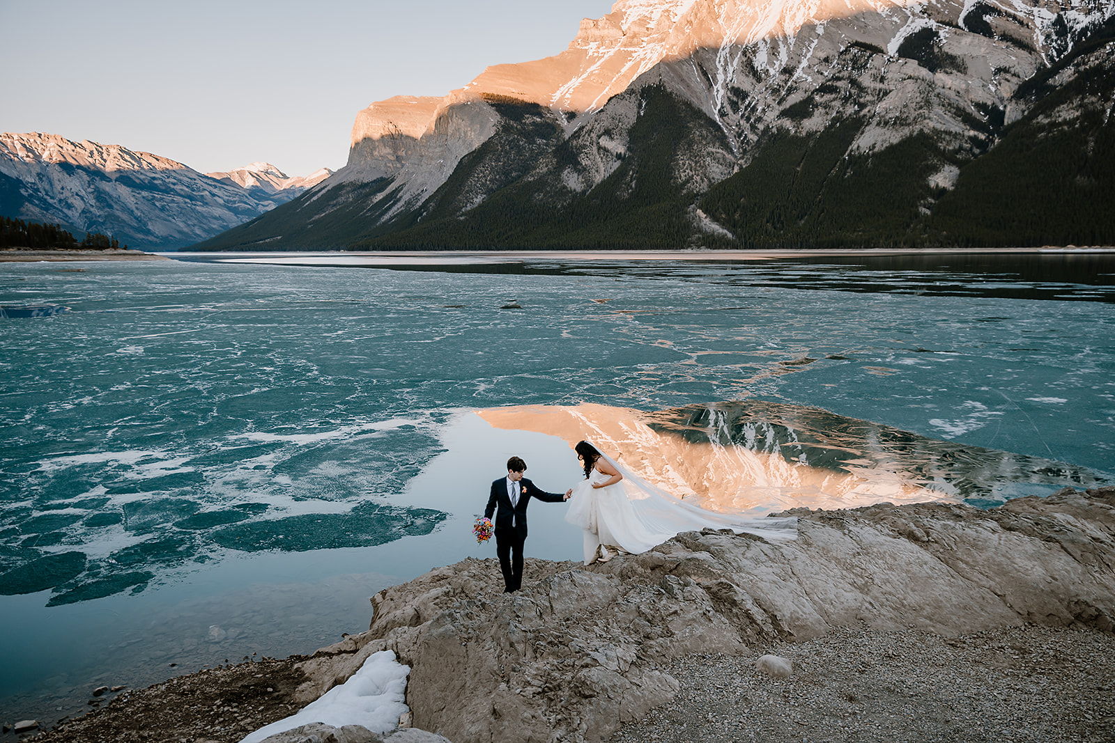 get-married-in-Banff groom helping the bride step down rocks during their winter mountain wedding