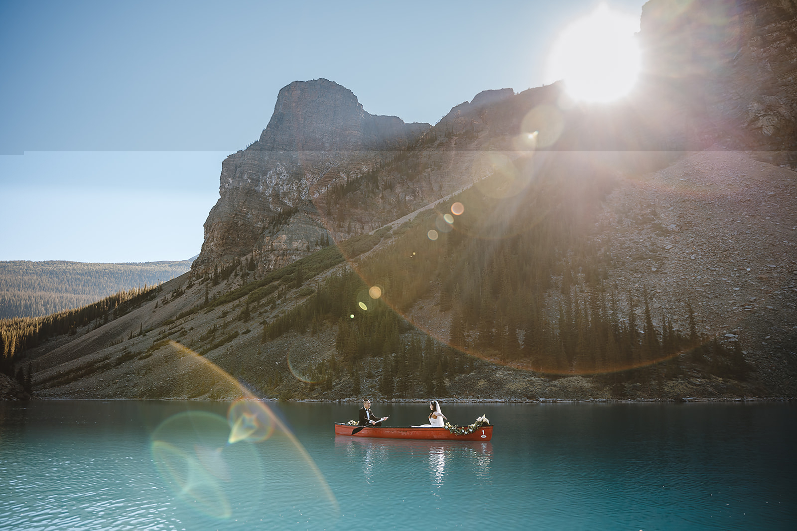 get-married-in-banff a couple riding in a red canoe on blue waters while they get married in Banff | how to get married in banff